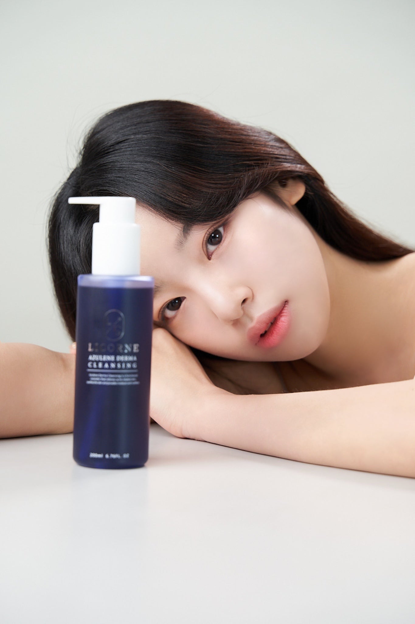 Woman with a bottle of skincare product on a white background