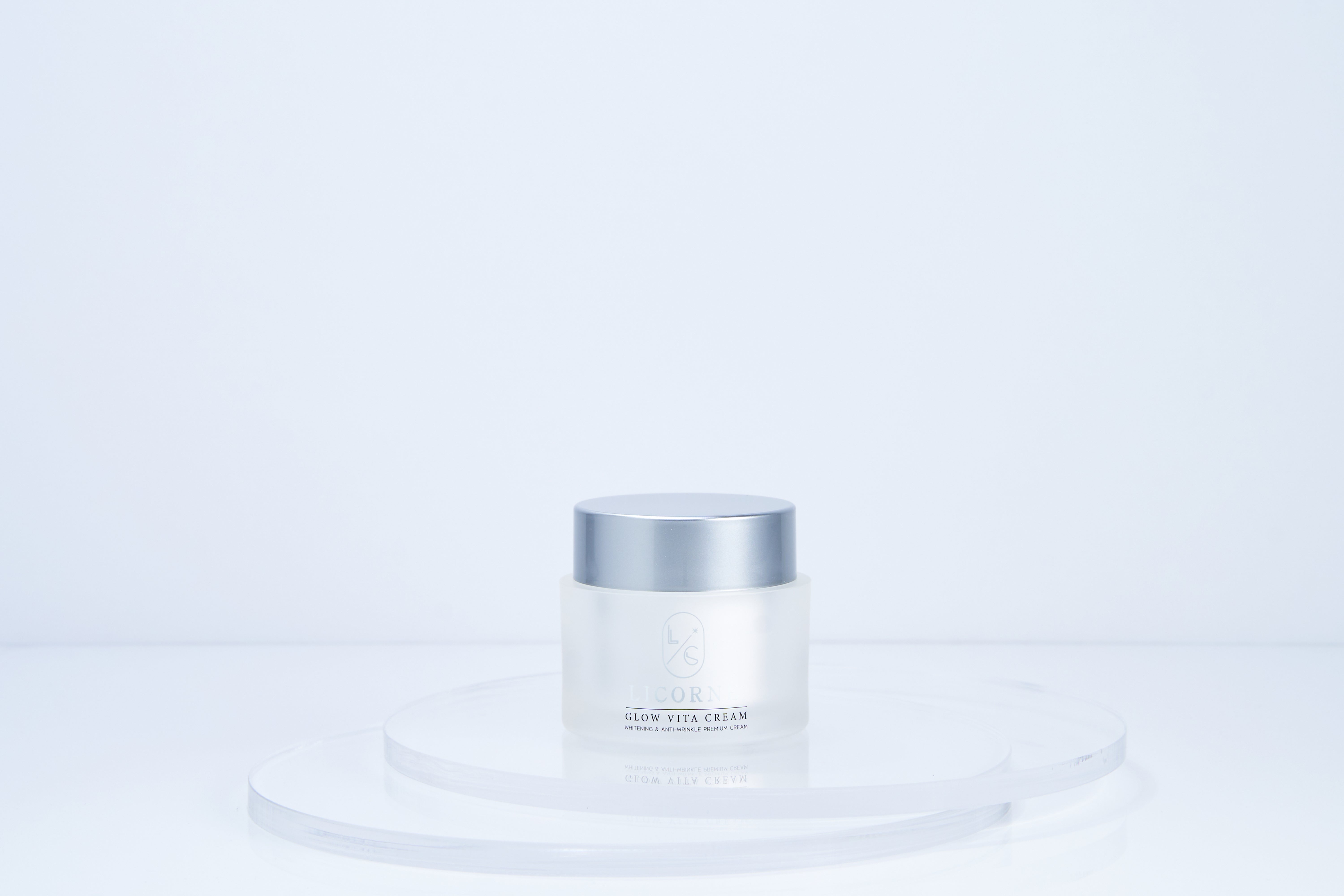 White skincare jar with silver lid on a light blue background