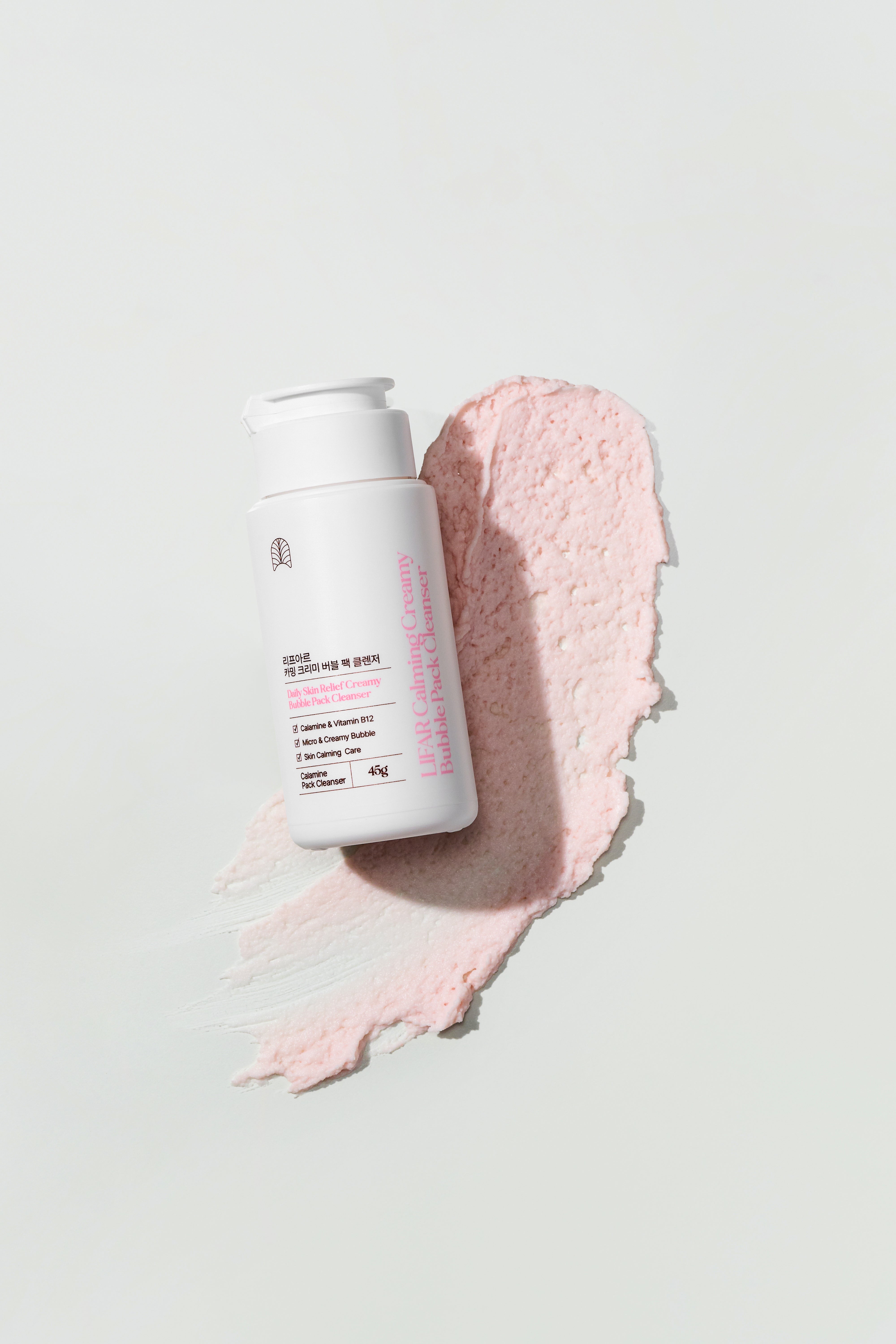 Skincare product with a pink smear on a light gray background