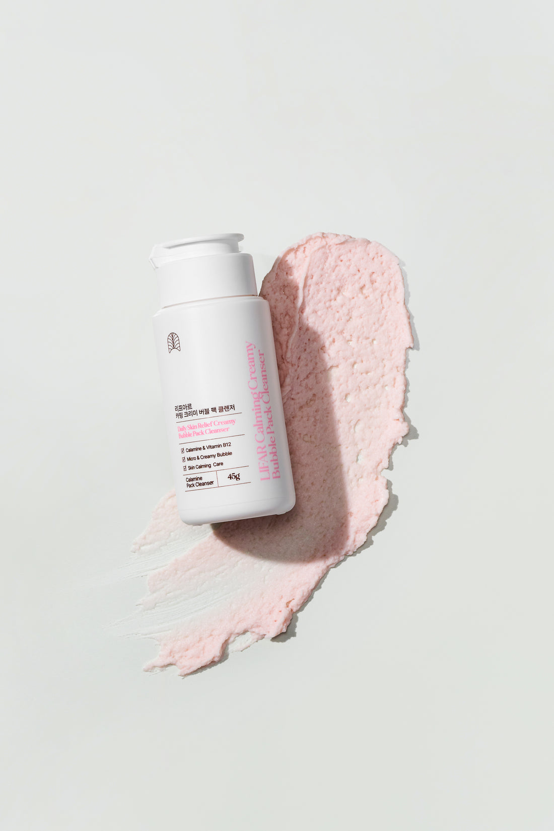 Skincare product with a pink smear on a light gray background