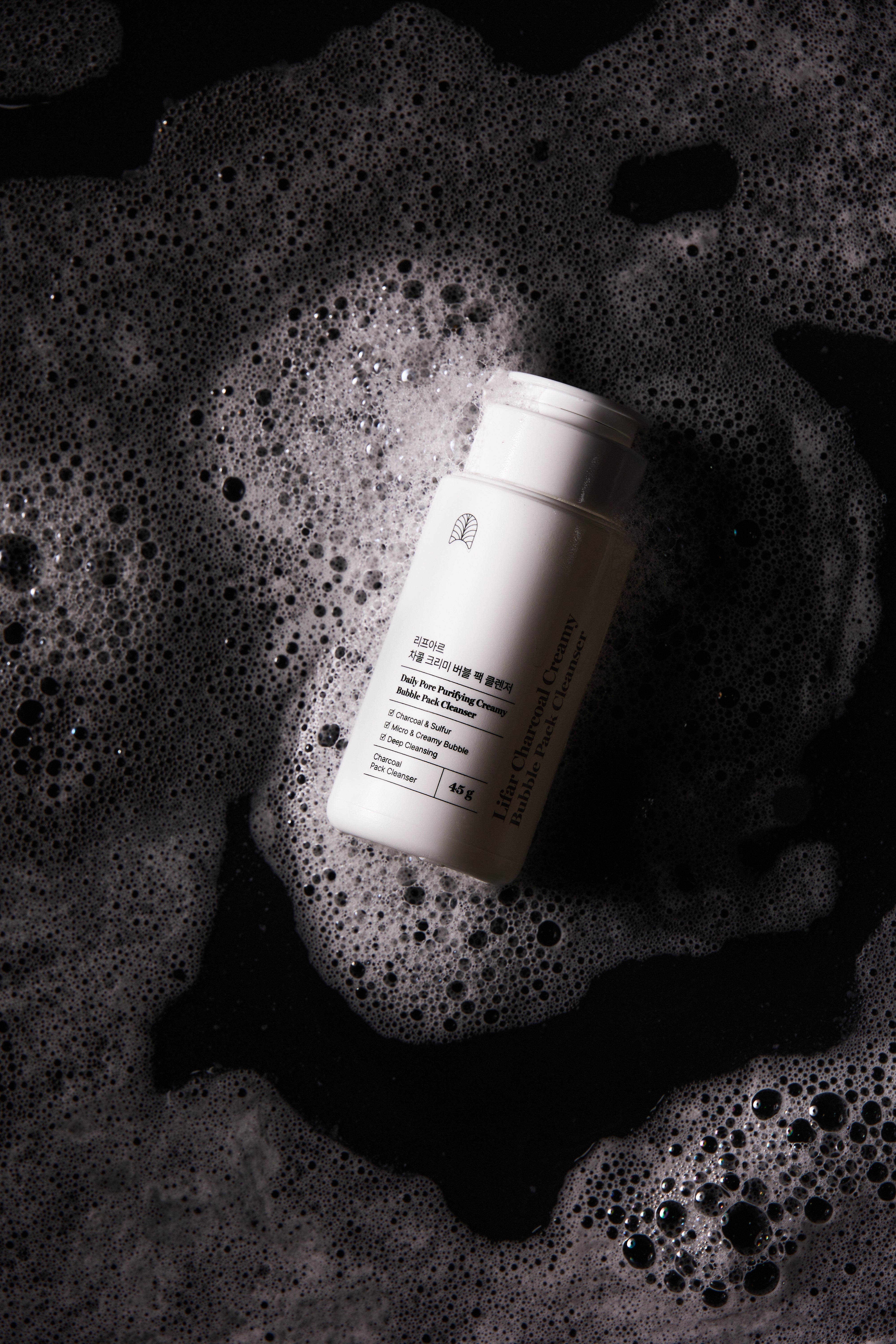 White bottle with label on a textured black surface with bubbles