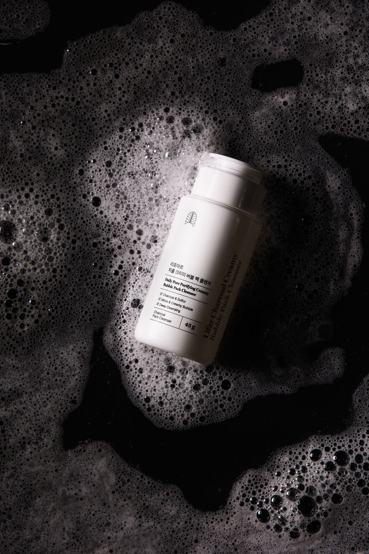 White bottle with label on a textured black surface with bubbles