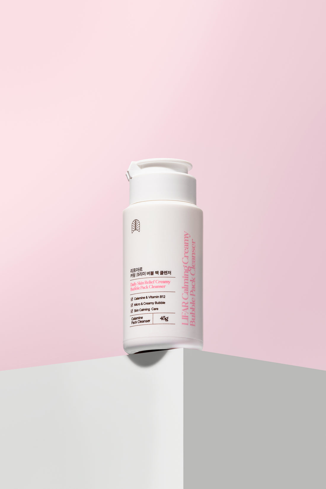 Skincare bottle on a pink and gray background