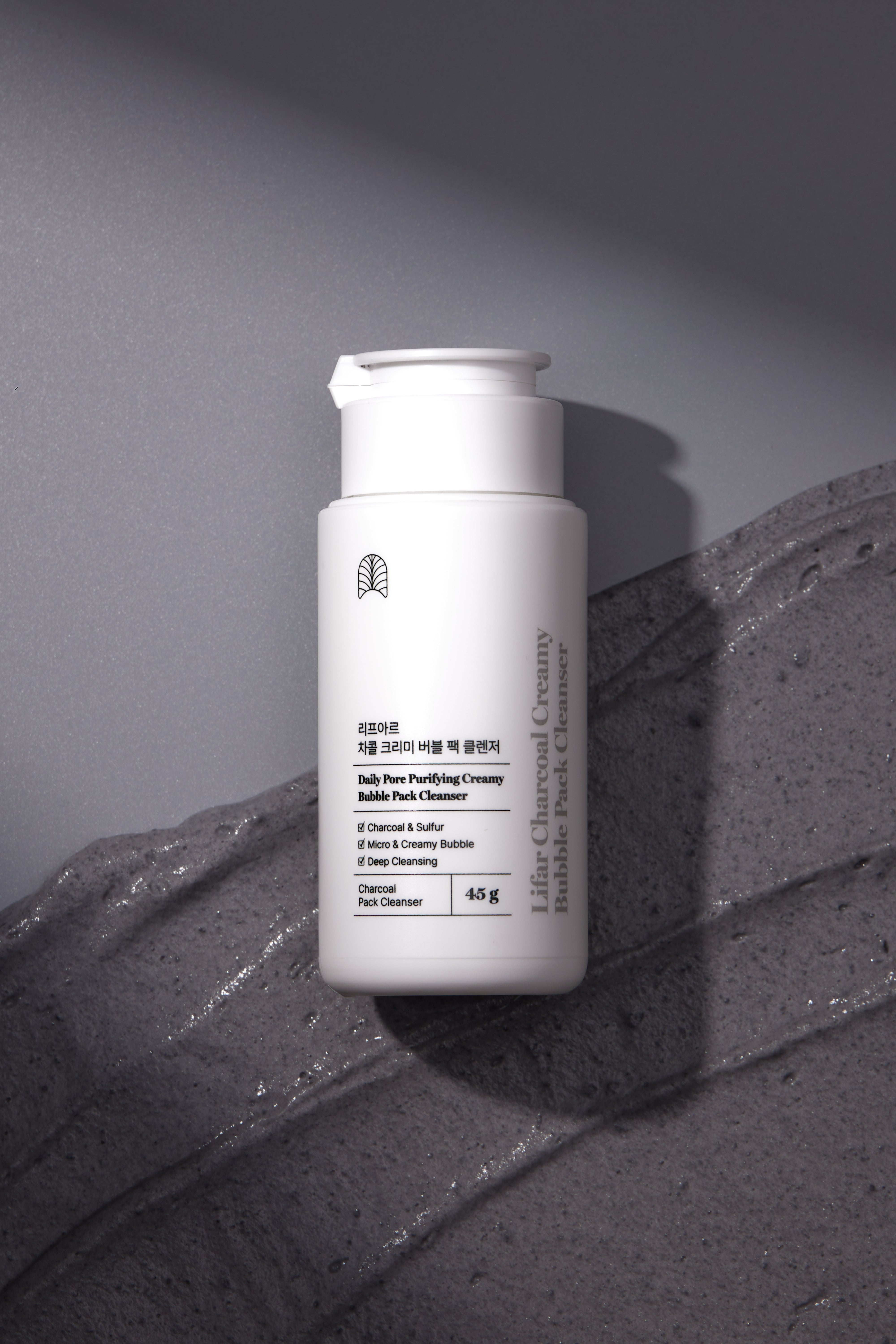 White skincare bottle with text on a textured gray surface