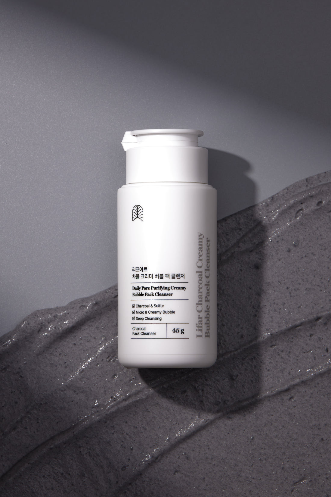 White skincare bottle with text on a textured gray surface