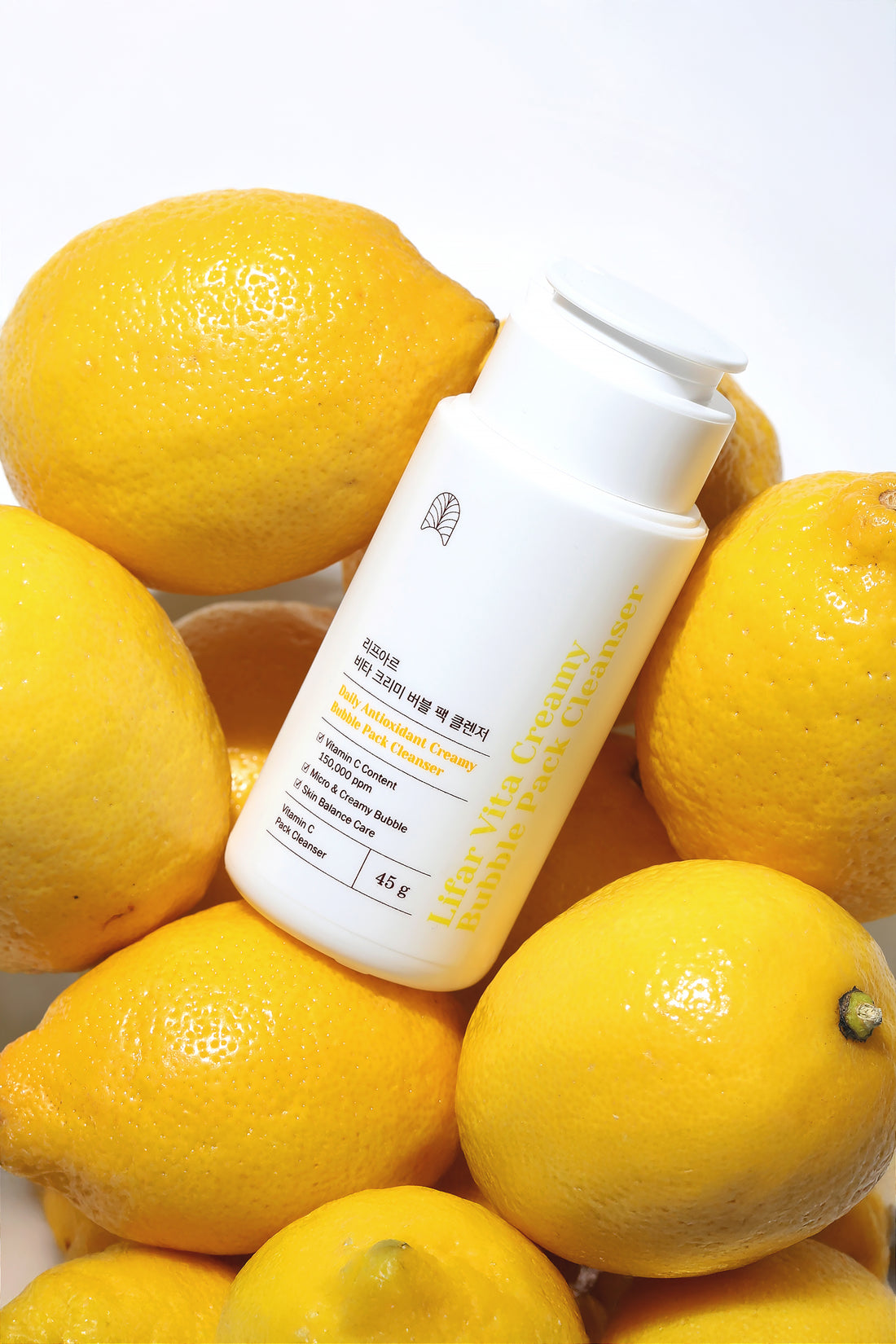 White bottle with a pump dispenser surrounded by lemons on a white background