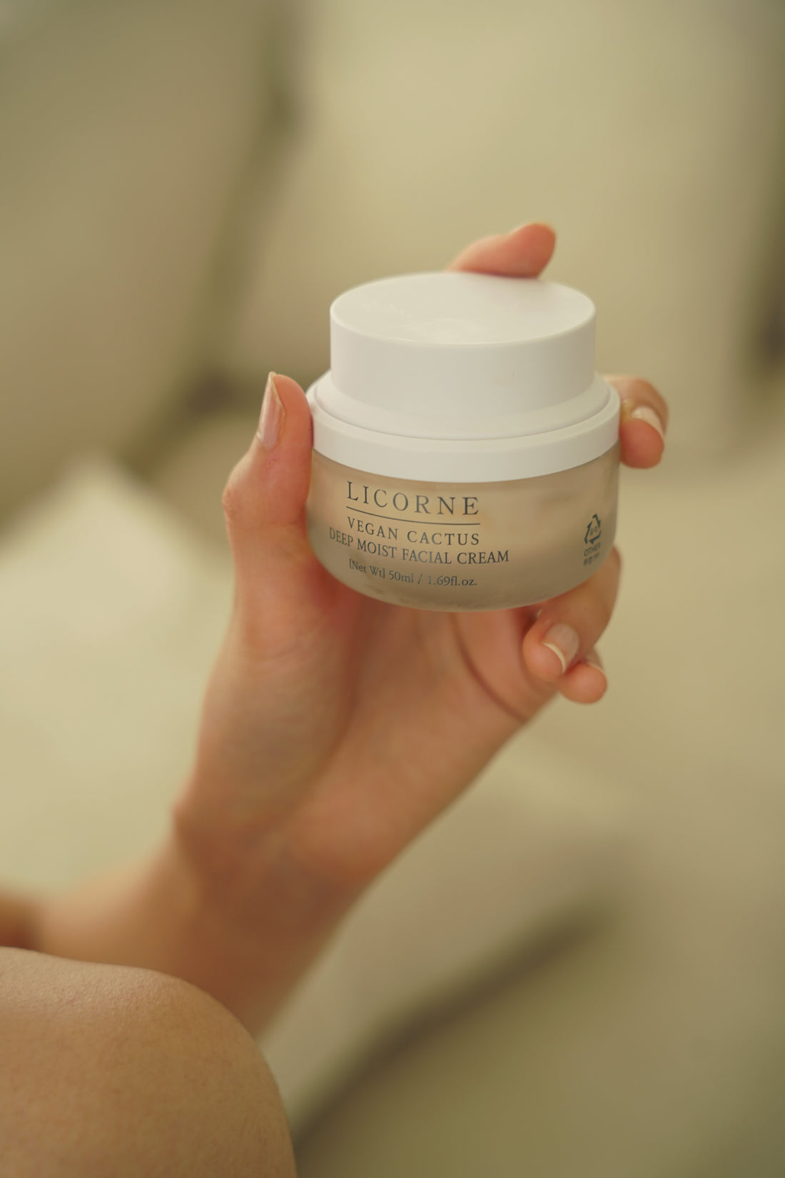Hand holding a jar of Licorne Vegan Cactus Facial Cream against a neutral background